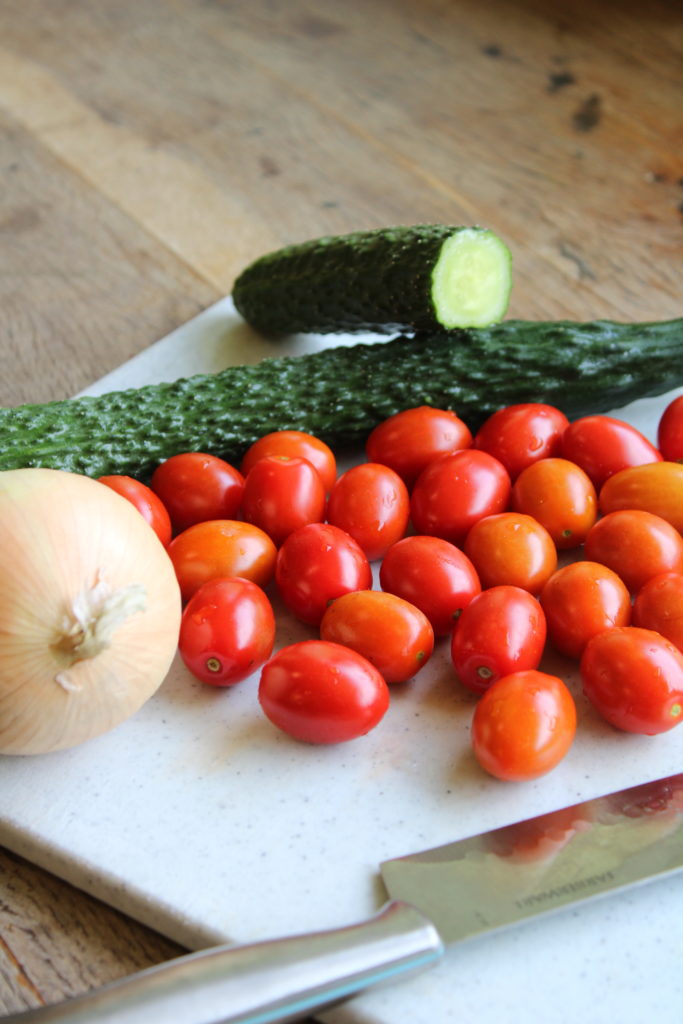 the ingredients to a cucumber and tomato pasta salad