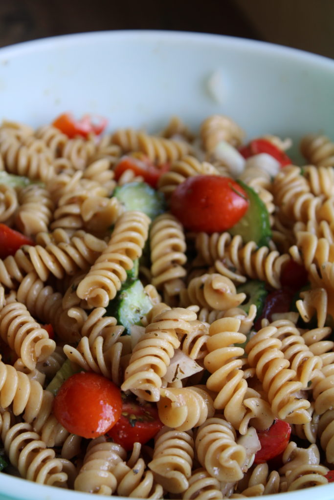 a bowl of cucumber and tomato pasta salad