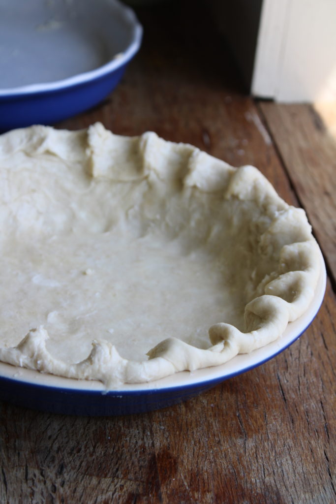 showing how to put the flaky pie crust in a pie pan 