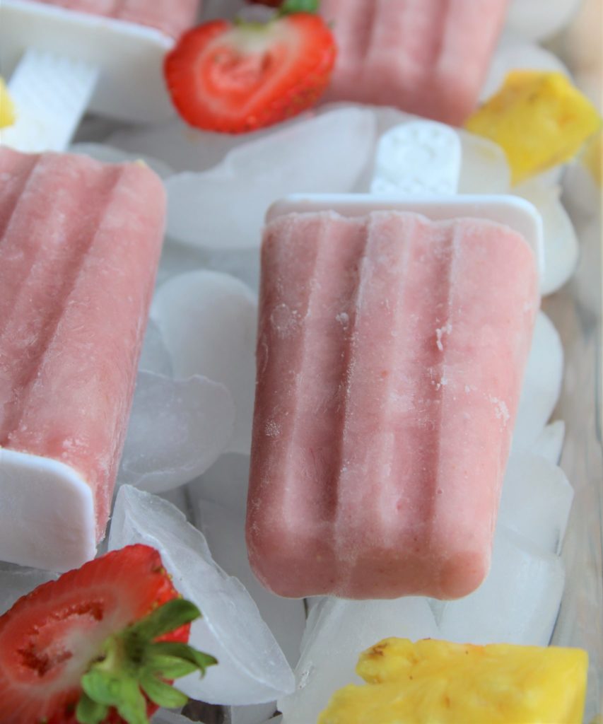 a homemade strawberry and pineapple popsicle on ice