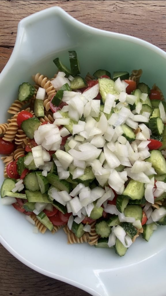 showing how to make a cucumber and tomato pasta salad